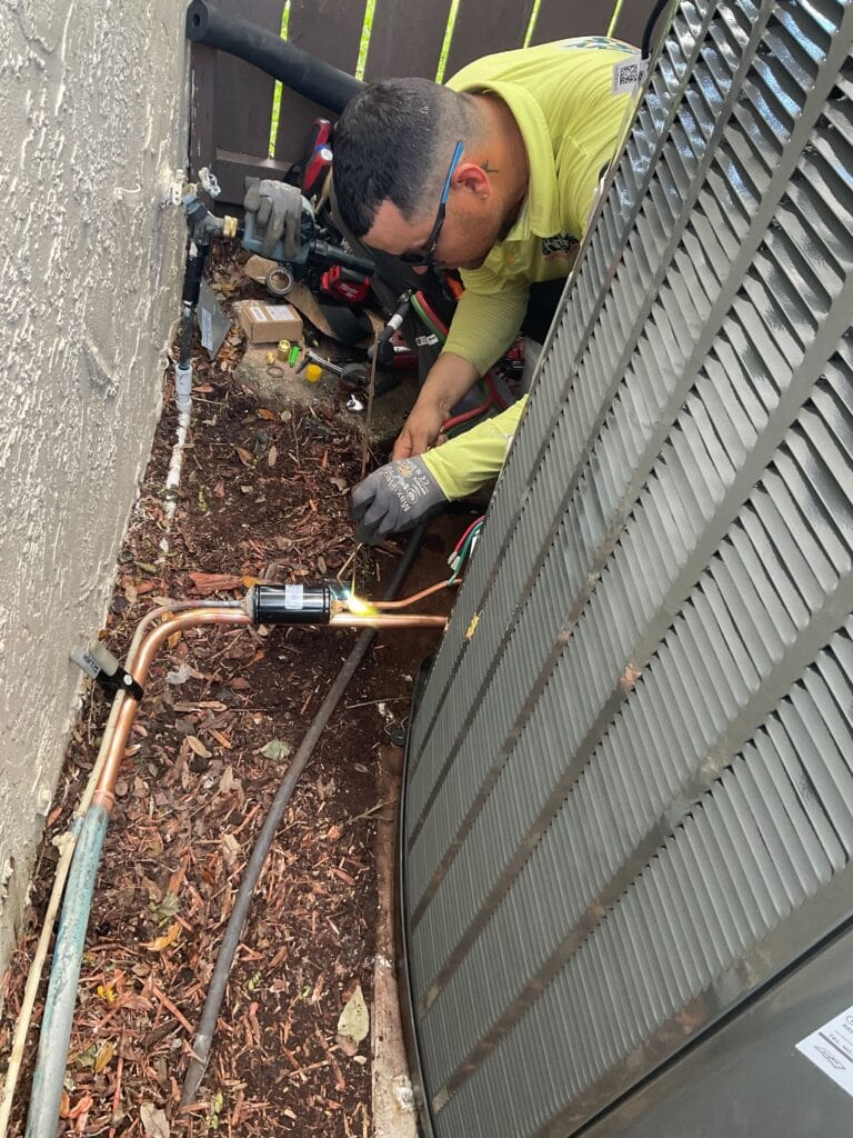 Sunny Bliss Plumbing & Air AC technician soldering HVAC unit during the installation process